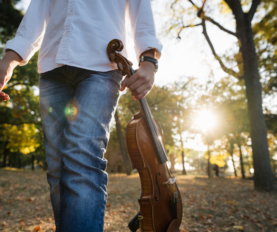 boy walking outside with violin
